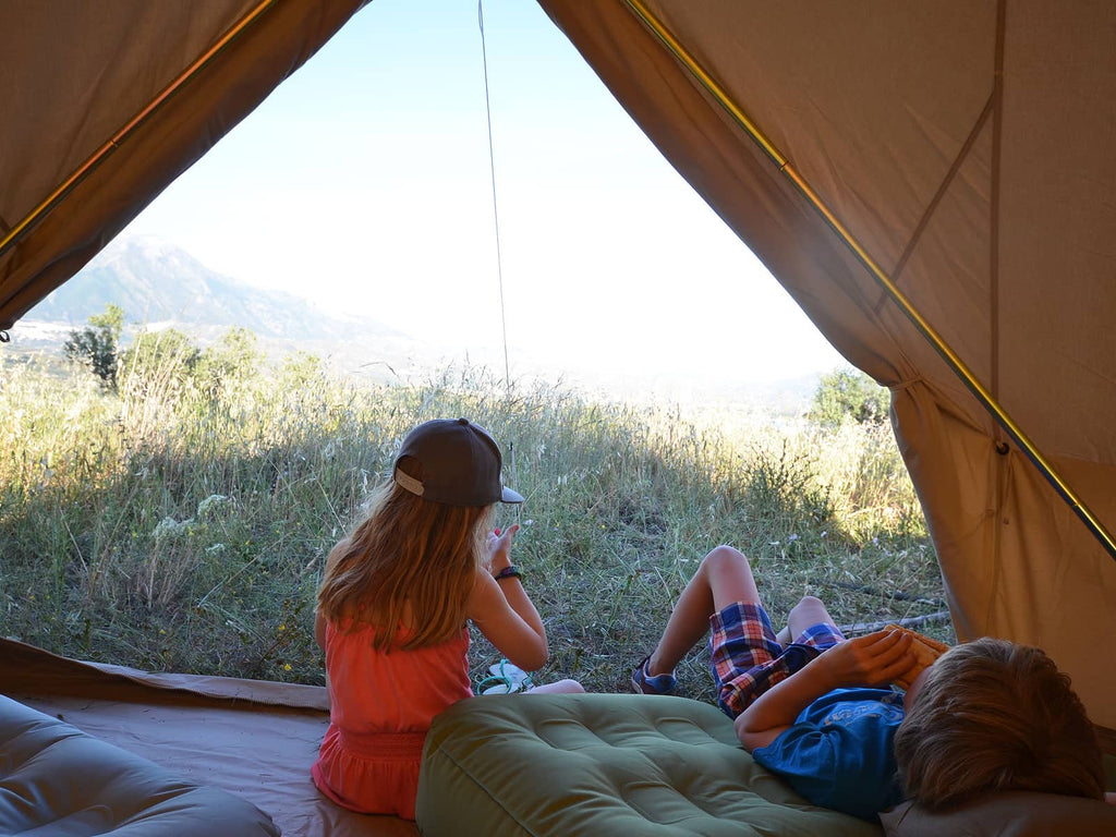 Children relaxing in the entrance of a 4.5m ultimate bell tent