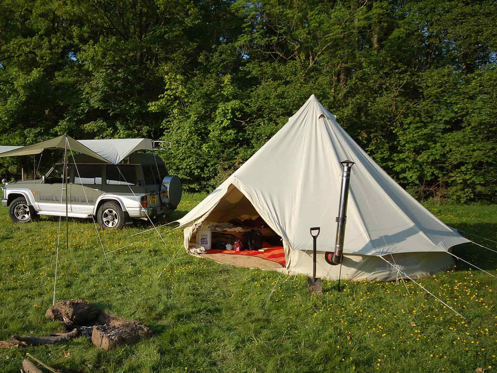 5m deluxe bell tent with stove pitched next to a jeep with malu awning