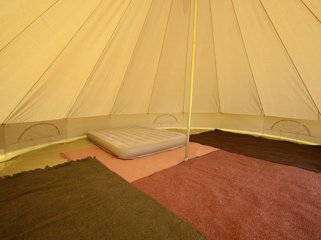 Inside a single pole 6m standard bell tent with double mattress and rugs
