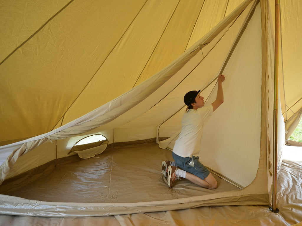 A person unzipping the partition of a 6m twin door bell tent inner tent