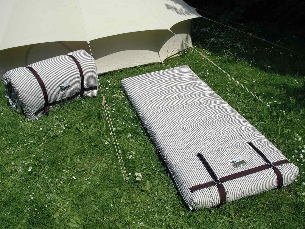 Two adult sized organic naturalmat camp bed's on the grass next to a bell tent
