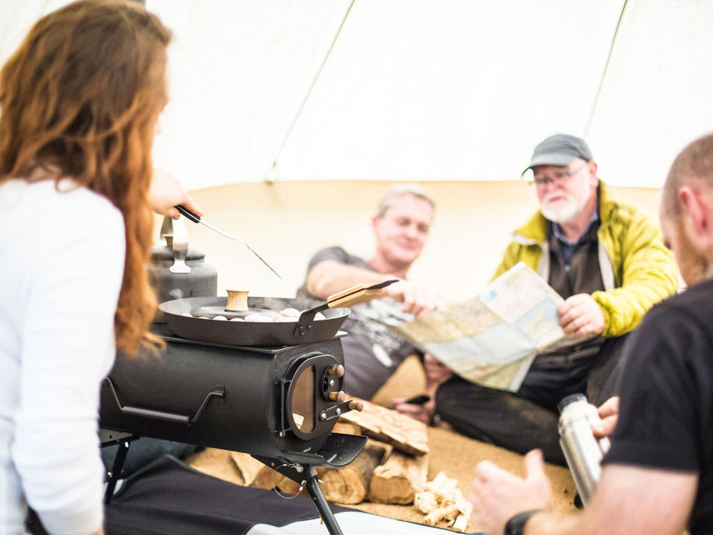 Group of people cooking breakfast on a frontier plus stove inside a bell tent 