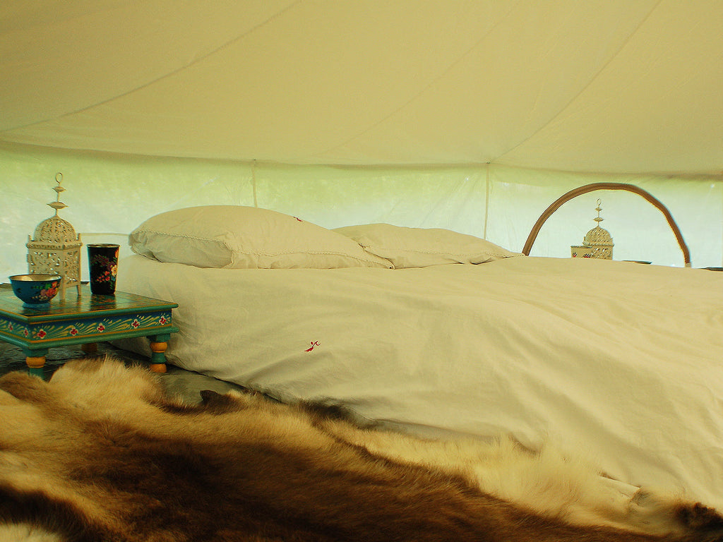 Double bed with side tables and lanterns inside a 5m bell tent inner tent