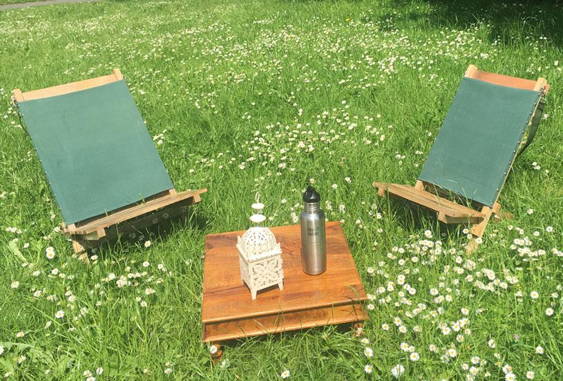 2 x portable hand-made deckchairs in a daiy field indian table with water bottle and lantern