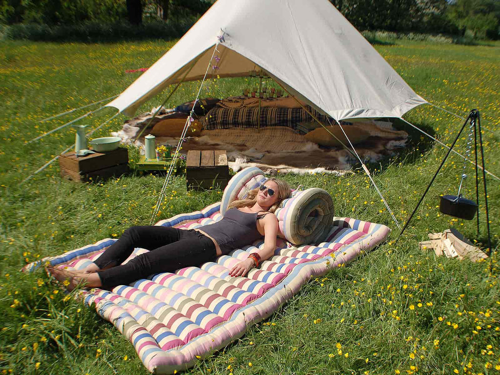 Relaxing on a double roll-up cotton mattress infront of a bell tent
