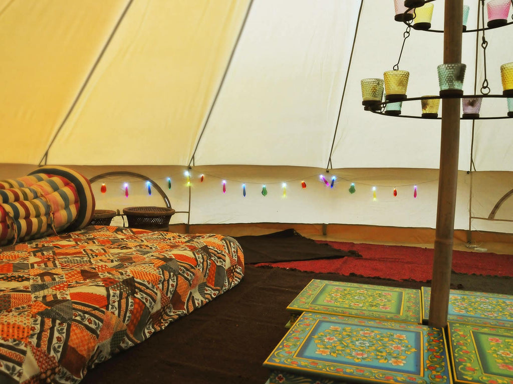 4m deluxe bell tent interior with bed, tealight chandelier and tables