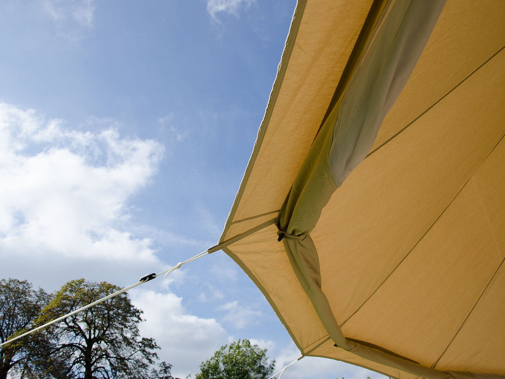 Under side view of a bell tent ceiling with walls rolled up