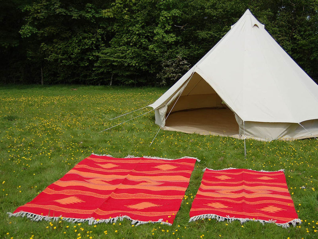 Two aztec handloomed rugs outside of a bell tent