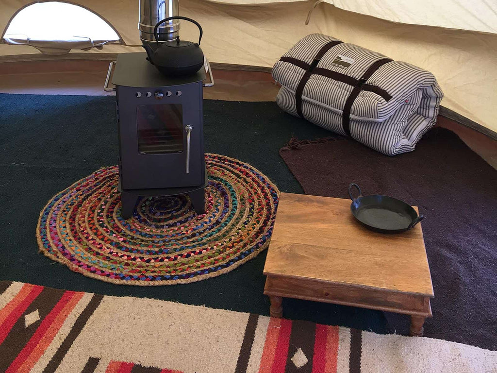 Bell tent with stove and handcrafted low-level varnished table