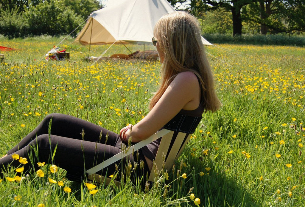 Sat in a meadow infront of a bell tent on an ergonomic portable chair