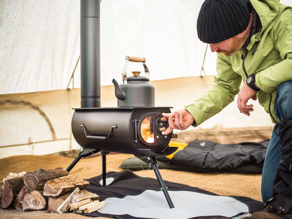 Person adjusting air flow of a frontier plus stove inside a bell tent