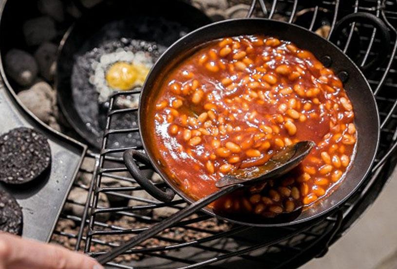 Cooking egg and beans in kadai skillets on a kadai firebowl