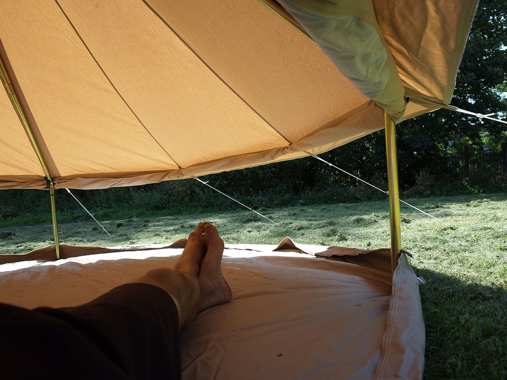 Person inside a 3m ultimate bell tent with walls rolled up