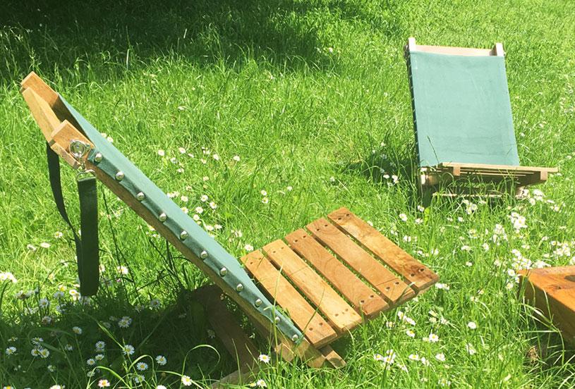 Two portable hand-made deckchairs in the long grass with daisies