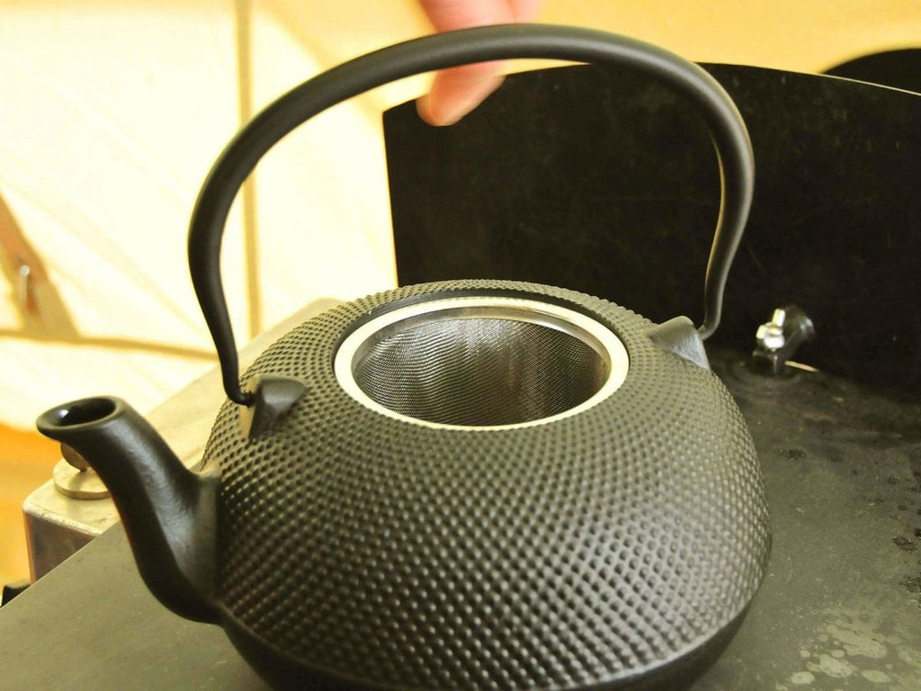Cast iron tea kettle on a bell tent stove