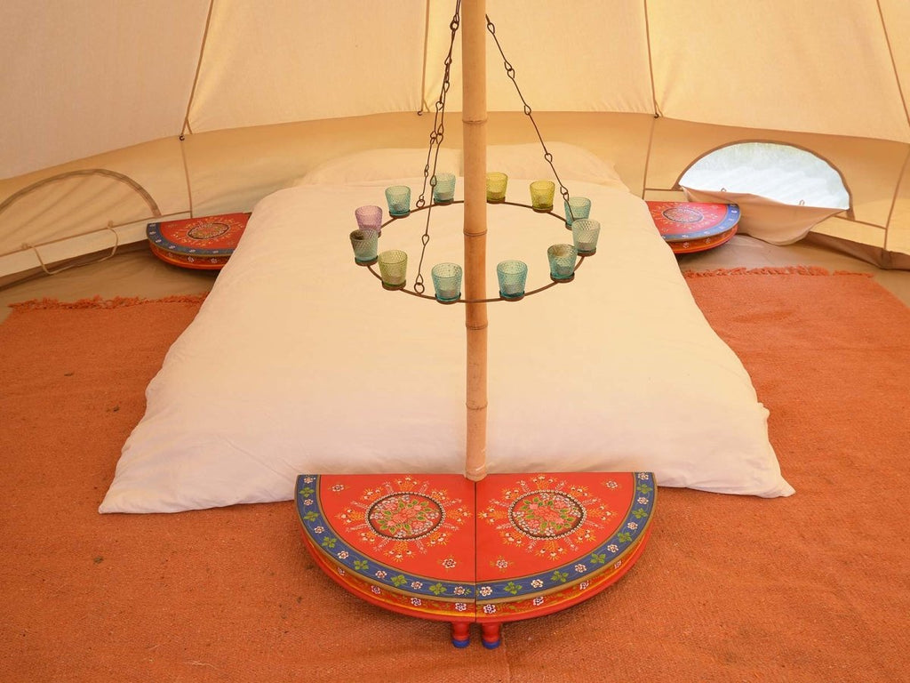 Four segments of round table positioned around bed inside a bell tent - Red